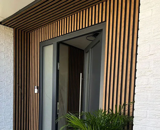 Moderne entree met houten lattenwand en strakke voordeur.